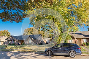 Typical residential street with parked car in front of residential house and colorful autumn leaves in Texas, USA