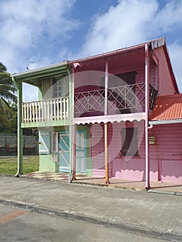 Typical rural Caribbean style houses with pink and green colored walls and headliner, shuttered windows and doors. Tropical