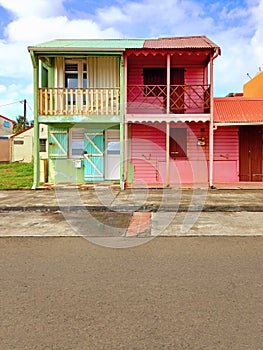 Typical rural Caribbean style houses with pink and green colored walls and headliner, shuttered windows and doors. Tropical