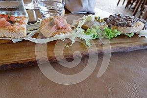 Typical rustic tuscan appetizer with meat and tomatoes crostini on a wooden tray . Italian starter