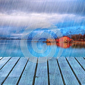 Typical scandinavian Red house on sea in fjord with platform dock in rainy day.