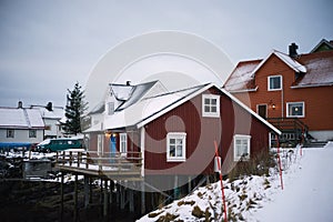 Typical scandinavian red houses at fjord in front of snow covered mountains in winter