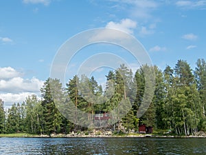 A typical scandinavian red wooden cottage on the shores of lake Saimaa in Finland