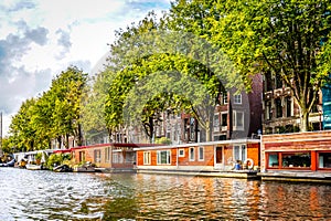 A typical sight of houseboats are lining the Waalseiland Canal near the Montelbaans Tower in the old city center of Amsterdam