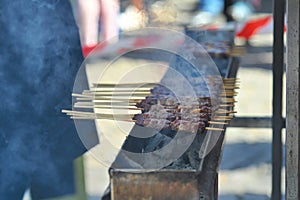 Typical skewers of lamb arrosticini cooking on a charcoal grill barbecue close up view
