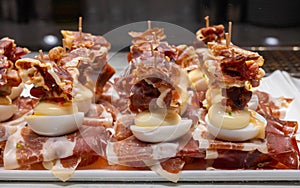 Typical snack of Basque Country, pinchos or pinxtos, small piece of bread on skewers with egg, jamon and different toppings,