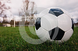 Typical soccer ball on the free kick marking line, outdoors on the stadium field. Traditional football ball on the green grass