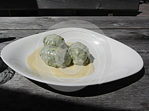 Typical South Tyrolean dish of canederli pasta with cheese sauce on rustic outdoor wooden table at summer