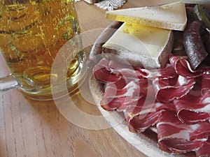 Typical South Tyrolean snack with speck, mountain cheese, smoked sausages and a cold mug of light beer