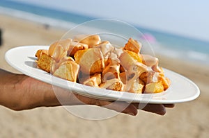 typical spanish patatas bravas, fried potatoes with a hot sauce, on the beach photo
