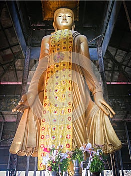 Typical standing golden Buddha statue in a typical holy shrine w