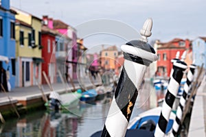 Typical street scene showing brighly painted houses, mooring posts and canal on the island of Burano, Venice.