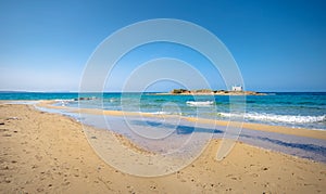 Typical summer image of an amazing pictorial view of a sandy beach and an old white church in a small isl