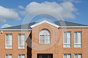 A typical two-story Australian home with multiple windows. The exterior of a suburban brick house.