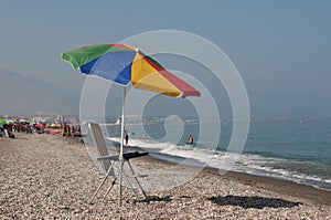 Typical umbrella and chair on spanish rocky beach