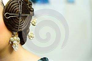 Typical Valencian fallera bun, traditional Spanish hairstyle and decorative earrings, negative space for text photo