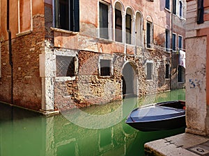 A typical venetian canal crossing and a tiny boat moored along the house wall