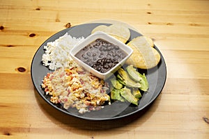 Venezuelan breakfast scrambled eggs with tomato called Perico, black beans, hard white cheese, arepas and avocado photo