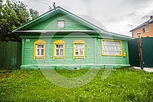 A typical village house in the countryside. Green wooden vintage home with yellow windows. City of Dmitrov, Moscow Region, Russia