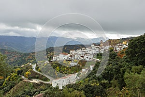 Typical white Andalusian village,pueblo blanco, with view of the mountains. Cloudy misty autumn day. White houses red roof.Urban