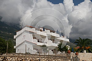 Typical white villa with appartments and acoomodation for tourists, below the hills, view on the sky
