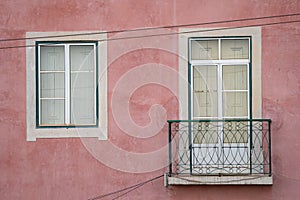 Typical window and balcony with pink buildng exterior facade, in Lisbon Portugal