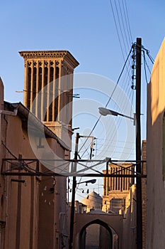 Typical Windtower made of clay taken in the streets of Yazd, iran, surrounded by power electrical lines.