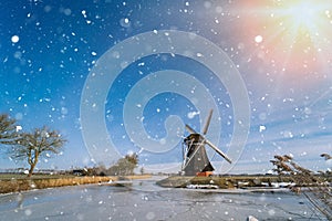 Typical winter dutch landscape with windmill. frozen canal in netherlands. Traditional winter holland scene. winter snow