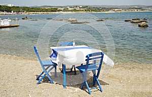 Typically Greek blue restaurant table and chairs beside the sea photo