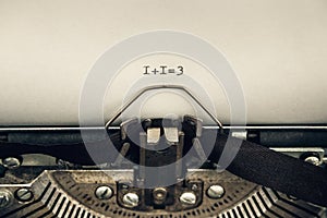Typing numerals 1 plus 1 equally 3 on a vintage typewriter close-up. concept of teamwork