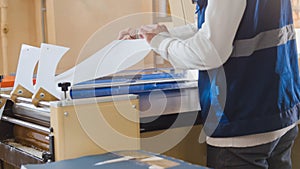 The typography worker pulls the paper from the machine