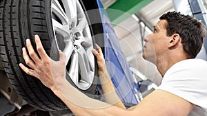 Tyre change in a car repair shop - worker assembles rims on the