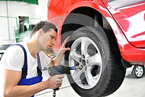Tyre change in a car repair shop - worker assembles rims on the photo