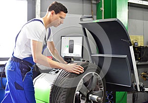 Tyre change in a garage - assembler balancing a tyre on the mach