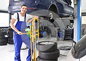 Tyre change in a workshop - portrait mechanic with stack of tyre