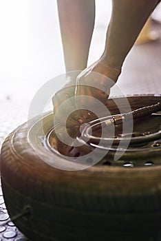 Tyre, hands and wheel in garage for repairs, rubber and fixing or replace fitting on car at shop. Closeup, person and