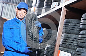 Tyre replacement. mechanic holding tire in store warehouse