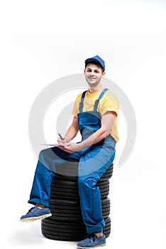 Tyre service worker sitting on a pile of tires