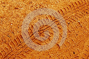Tyre track on sand in orange color.