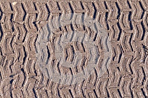 Tyre tracks on sand in brown tone.