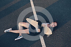 Tyred skater girl sleeping on asphalt in warm summer day