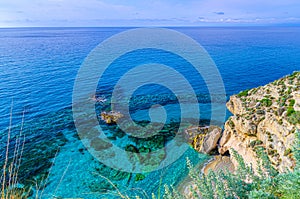 Tyrrhenian sea with turquoise azure water and reef, endless horizon, view from cliff rock of Tropea town