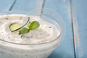 Tzatziki in bowl on a blue wooden table