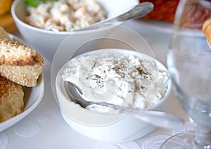 Tzatziki sauce. Greek yogurt cucumber dip in white bowl over table. photo
