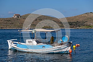 Tzia, Kea, Greece. Blue and white traditional fishing boat anchored in the middle of calm sea at Vourkari cove