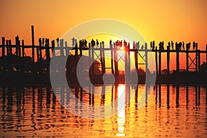 U Bein Bridge at sunset with people crossing Ayeyarwady River, M