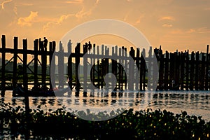 U Bein Bridge at sunset with people crossing Taungthaman lake, M