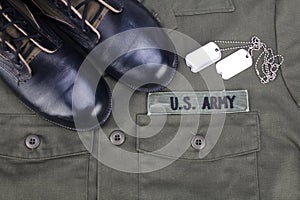 U.S. Army Branch Tape with dog tags and boots on olive green uniform photo