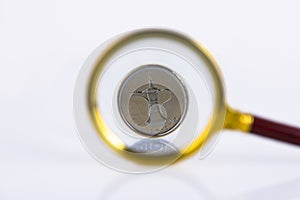 UAE currency dirham coin close up through magnifying glass on white background. Copy space