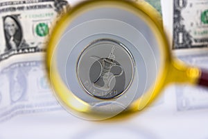 UAE currency dirham coin, view through a magnifying glass against the background of American dollars. Copy space